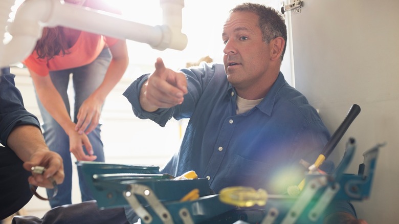 A plumber pointing at pipes