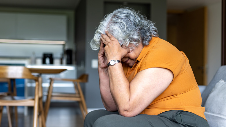 Senior woman looking worried while sitting on a couch