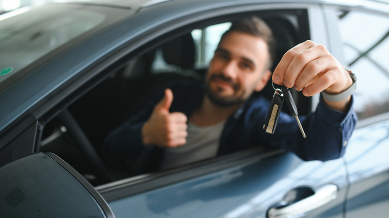 man giving thumbs up in car holding keys