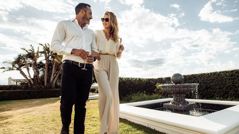wealthy couple walk through a garden