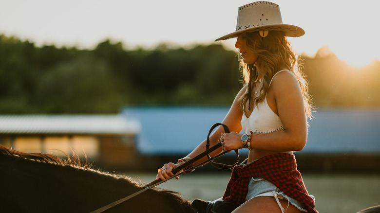 A woman on horseback at sunset.