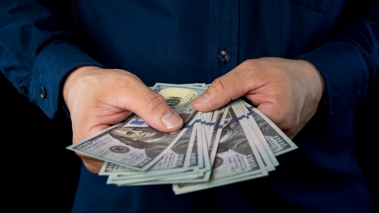 Big pile of money dollars in hand of businessman