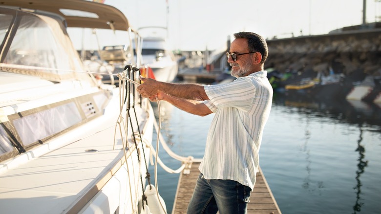 A man securing a boat with ropes at a marina dock