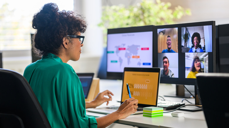 A Gen X woman sitting in front of computer sceens while attending a webinar