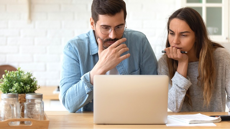 Couple looking serious reading laptop