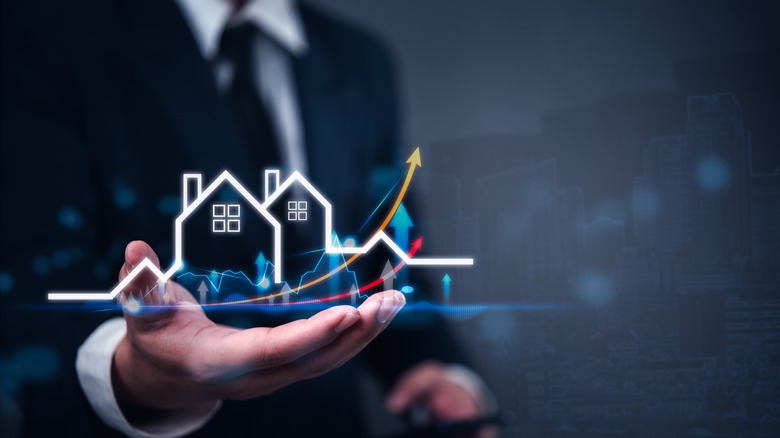 man's hand holding image of house and upward price arrows