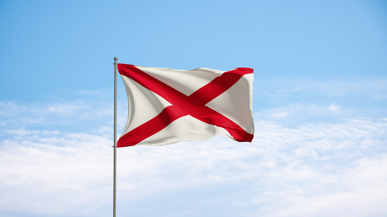 Alabama state flag flapping against a blue sky.
