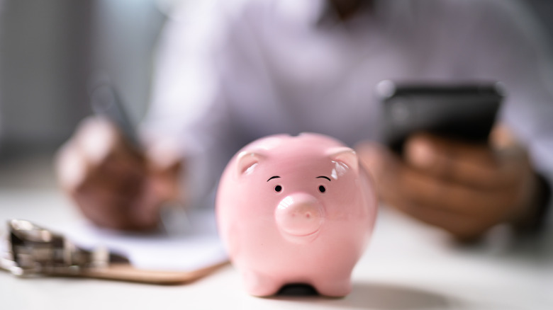Person sitting down with piggy bank in front