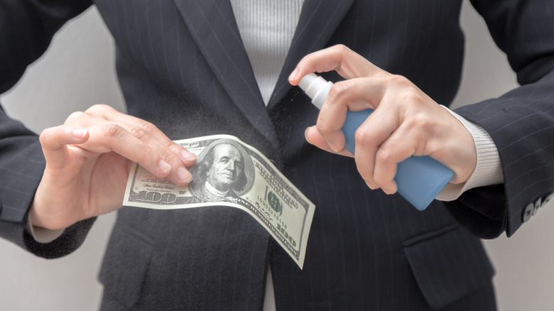 hands disinfecting money