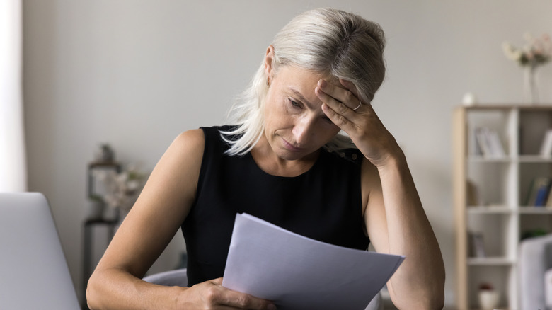 A senior women holding her head in distress while reading a letter