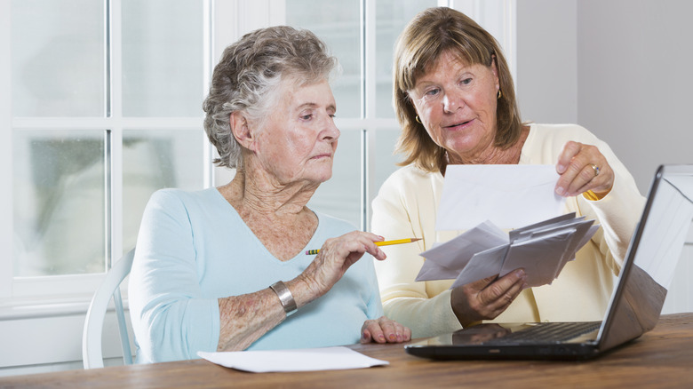 Woman helping elderly parent with bills
