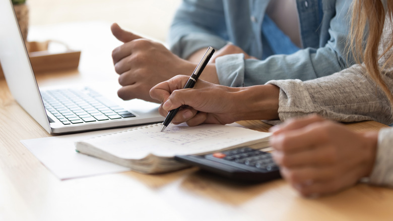 A couple budgeting with a computer, calculator, and notebook