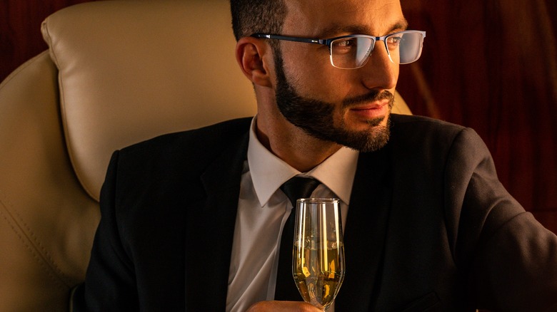 Handsome businessman wearing elegant suit flying on exclusive private jet.