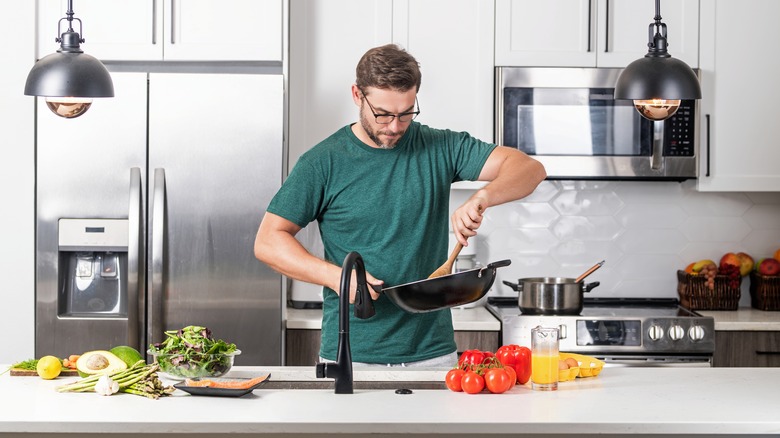 Private chef cooking with pan in kitchen.