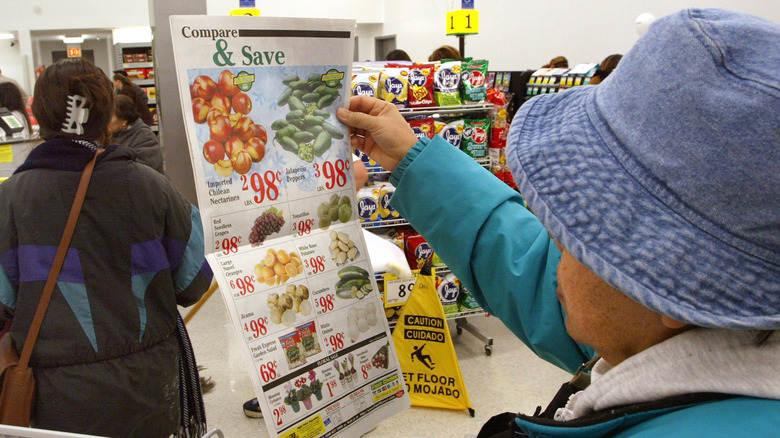 A woman looking at a grocery store flyer