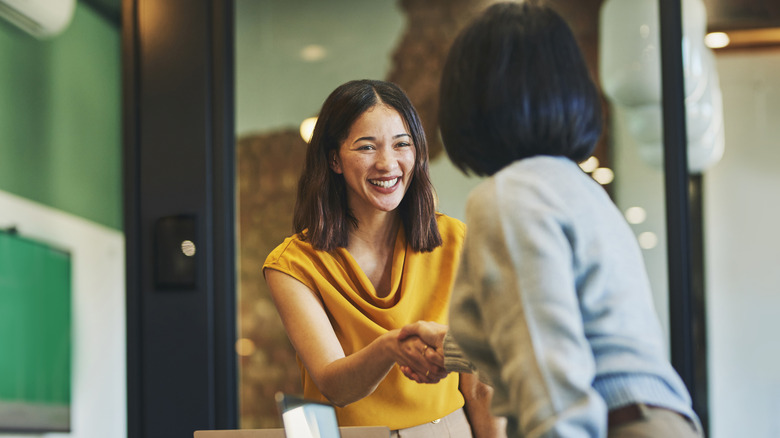 Two business women shake hands.