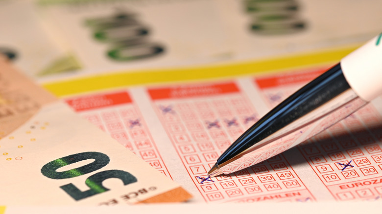Pen crossing out numbers on a lottery ticket