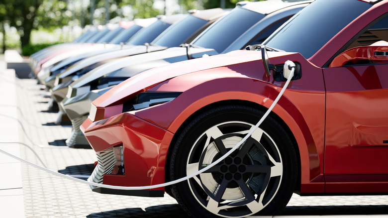 red EV being charged parked along row of EVs