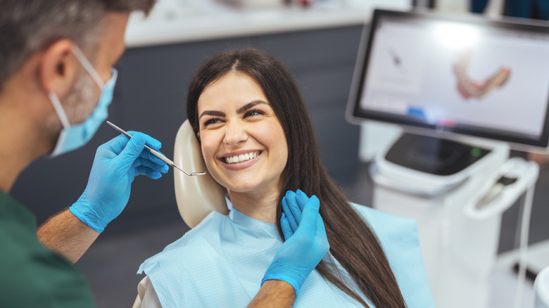 A patient in a dentist's chair smiling at her dentist.