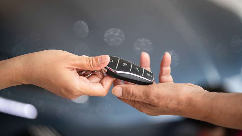 Person handing car key fob to someone