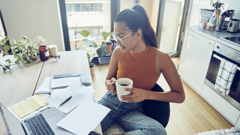 Close up of a woman at her home, holds coffee cup and finishing paperwork