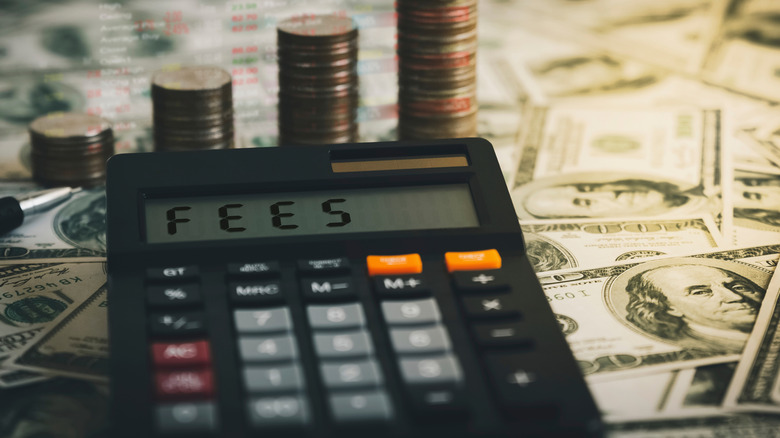 Calculator with the word FEES on the calculator placed on the dollar,