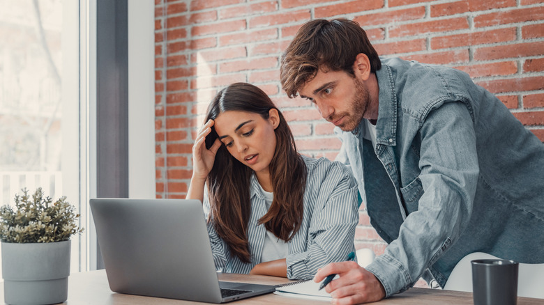 A  millennial couple who look to be frustrated with what they are looking at on a laptop
