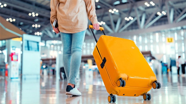 Person standing with orange suitcase