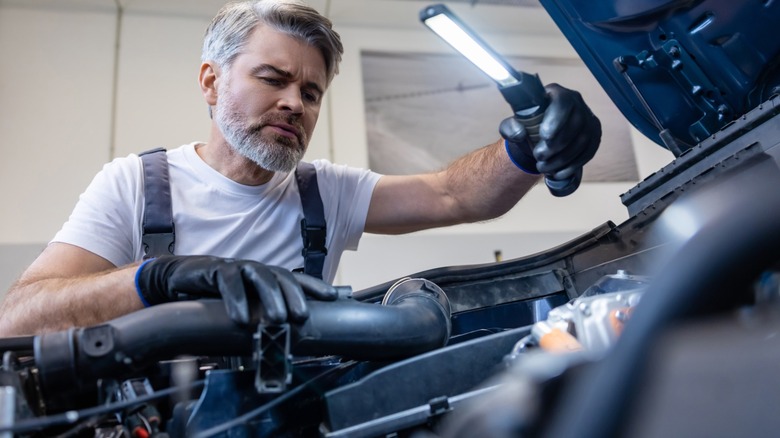 Mechanic holding a light in an open engine bay