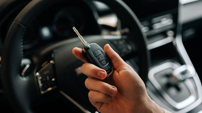 Hand holding a car key inside a vehicle